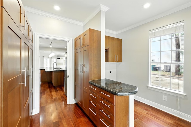 263 S Crimson Clover Ct, The Woodlands, TX 77381 - kitchen with dark wood finished floors, brown cabinets, crown molding, dark stone countertops, and recessed lighting