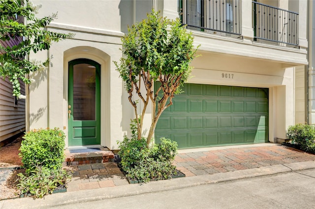 9617 Pemberton Crescent Dr, Houston, TX 77025 - doorway to property featuring an attached garage, stucco siding, a balcony, and decorative driveway
