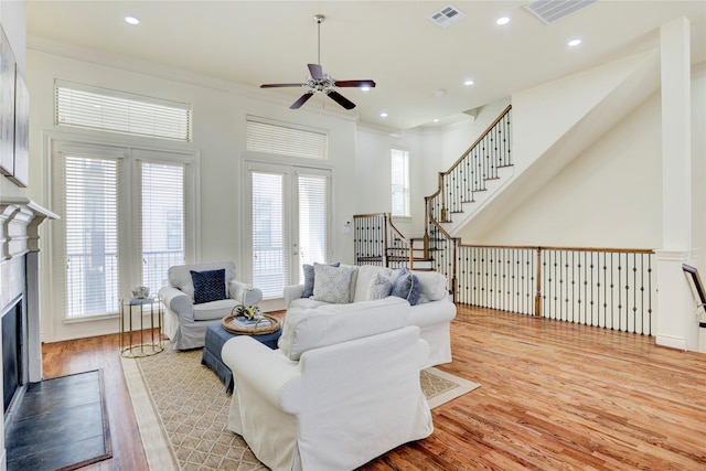 9617 Pemberton Crescent Dr, Houston, TX 77025 - living room featuring a ceiling fan, ornamental molding, a fireplace with flush hearth, wood finished floors, and stairway