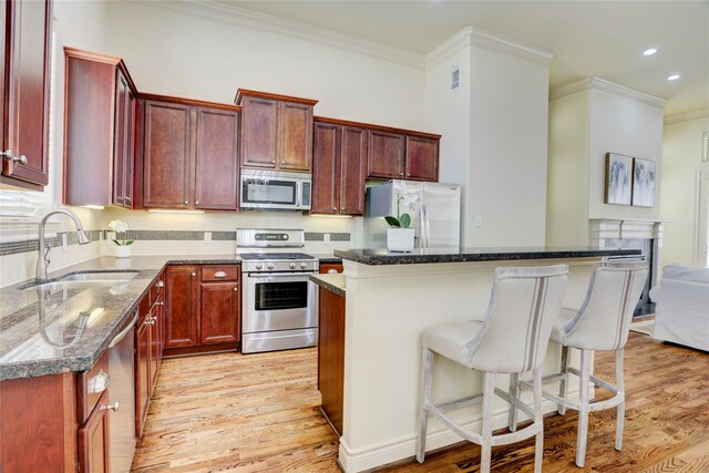 9617 Pemberton Crescent Dr, Houston, TX 77025 - kitchen with stainless steel appliances, ornamental molding, reddish brown cabinets, a sink, and light wood finished floors