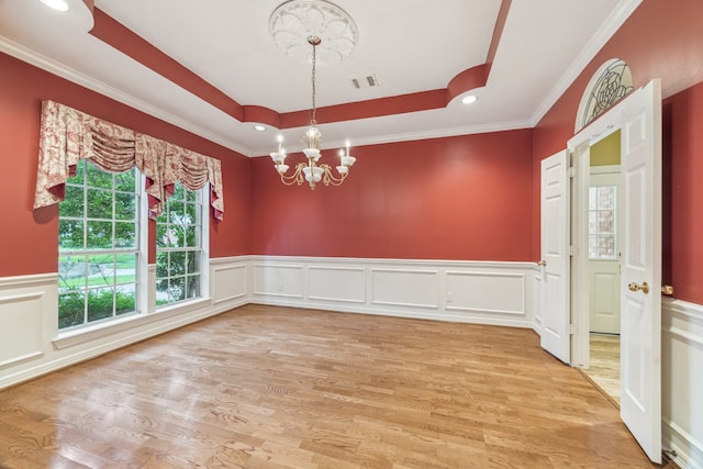 6010 Maple Knob Ct, Kingwood, TX 77345 - empty room with a chandelier, light wood-type flooring, a tray ceiling, wainscoting, and ornamental molding