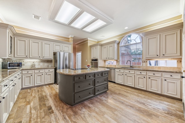 6010 Maple Knob Ct, Kingwood, TX 77345 - kitchen with stainless steel appliances, ornamental molding, cream cabinetry, backsplash, and light wood-style floors