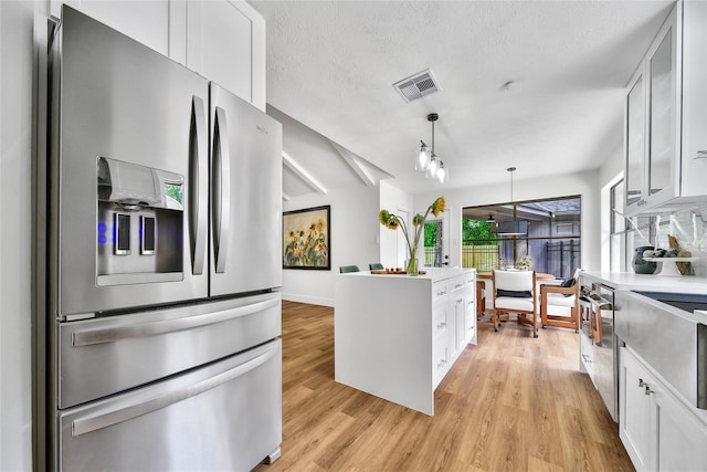 3022 Grove Terrace Dr, Houston, TX 77345 - kitchen with stainless steel fridge, white cabinetry, light wood-style floors, hanging light fixtures, and light countertops