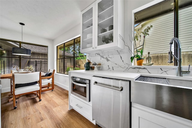 3022 Grove Terrace Dr, Houston, TX 77345 - kitchen featuring stainless steel appliances, a sink, light countertops, light wood-style floors, and glass insert cabinets
