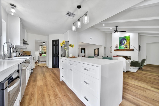 3022 Grove Terrace Dr, Houston, TX 77345 - kitchen with ceiling fan, a fireplace, white cabinets, and light wood finished floors