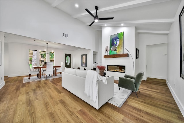 3022 Grove Terrace Dr, Houston, TX 77345 - living room featuring beamed ceiling, a glass covered fireplace, a chandelier, a ceiling fan, and light wood finished floors