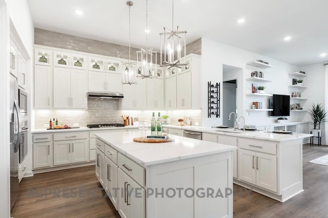 4315 Southpoint Way, Fulshear, TX 77441 - kitchen with under cabinet range hood, a center island, appliances with stainless steel finishes, a peninsula, and a chandelier