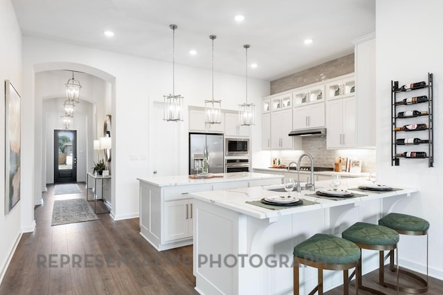 4315 Southpoint Way, Fulshear, TX 77441 - kitchen with appliances with stainless steel finishes, a peninsula, a center island, decorative backsplash, and glass insert cabinets