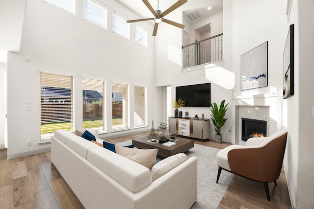 2326 Bristlegrass Dr, Katy, TX 77494 - living room featuring a ceiling fan, a high ceiling, light wood-style floors, and a glass covered fireplace