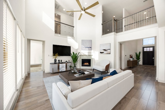 2326 Bristlegrass Dr, Katy, TX 77494 - living room featuring a high ceiling, a lit fireplace, ceiling fan, wood finished floors, and recessed lighting