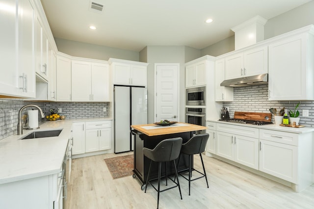 9715 Highland Pointe Dr, Needville, TX 77461 - kitchen featuring appliances with stainless steel finishes, under cabinet range hood, a sink, backsplash, and recessed lighting