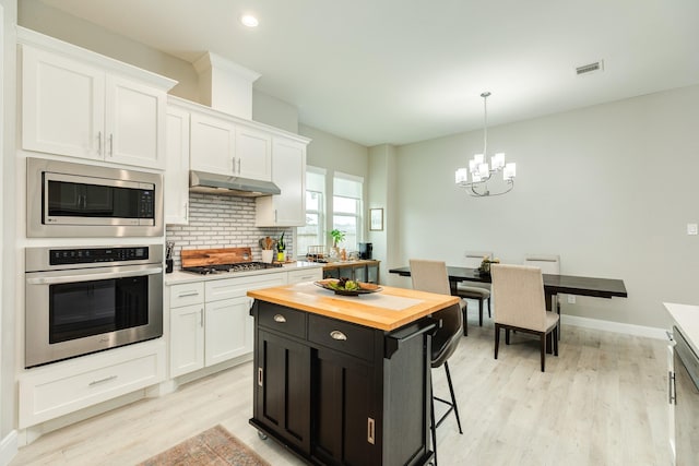 9715 Highland Pointe Dr, Needville, TX 77461 - kitchen featuring stainless steel appliances, butcher block countertops, under cabinet range hood, white cabinetry, and light wood-style floors