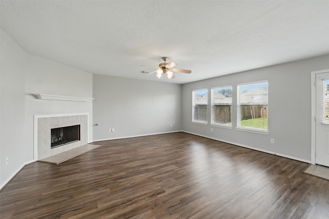 6419 Bonnie Chase Ln, Katy, TX 77449 - unfurnished living room featuring a ceiling fan, dark wood-type flooring, a fireplace, baseboards, and a textured ceiling