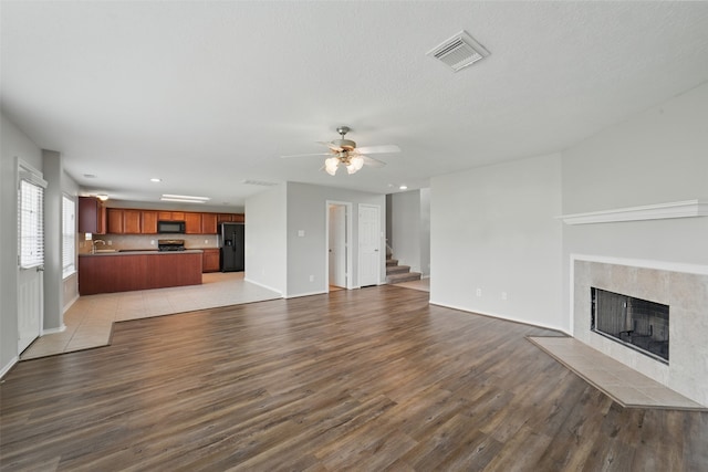 6419 Bonnie Chase Ln, Katy, TX 77449 - unfurnished living room featuring light wood finished floors, a tiled fireplace, baseboards, and recessed lighting