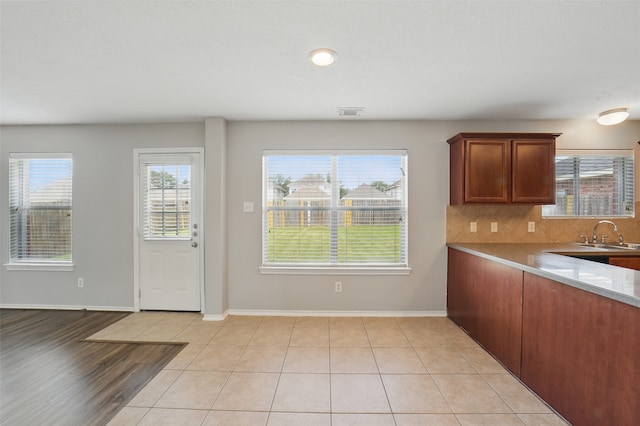 6419 Bonnie Chase Ln, Katy, TX 77449 - kitchen with a sink, baseboards, light countertops, brown cabinetry, and decorative backsplash