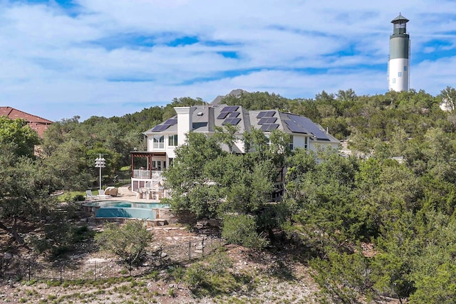 4315 Lago Viento, Austin, TX 78734 - rear view of house featuring solar panels, a balcony, an outdoor pool, and a wooded view
