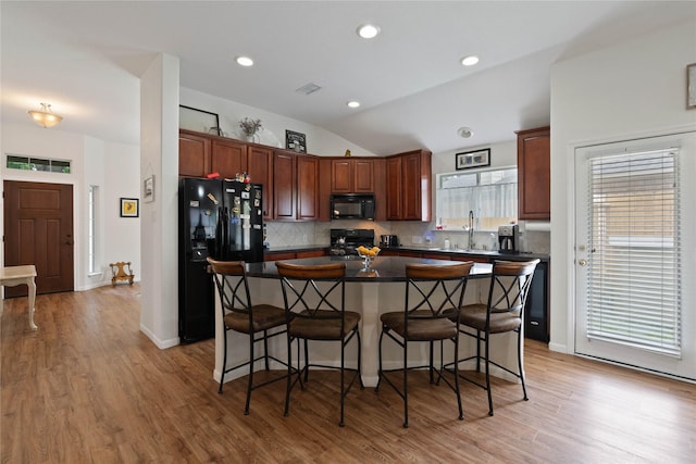 23 Drifting Shadows Cir, Conroe, TX 77385 - kitchen with black appliances, decorative backsplash, a breakfast bar, a center island, and lofted ceiling