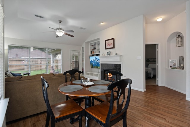 23 Drifting Shadows Cir, Conroe, TX 77385 - dining area featuring built in shelves, a tiled fireplace, wood finished floors, a ceiling fan, and baseboards