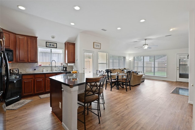 23 Drifting Shadows Cir, Conroe, TX 77385 - kitchen with range with gas stovetop, a sink, a kitchen breakfast bar, light wood finished floors, and backsplash