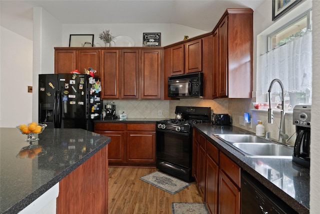 23 Drifting Shadows Cir, Conroe, TX 77385 - kitchen featuring black appliances, a sink, light wood-type flooring, decorative backsplash, and vaulted ceiling