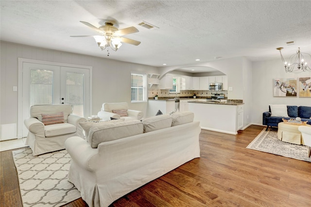 9327 Fairdale Ln, Houston, TX 77063 - living area with french doors, light wood finished floors, a ceiling fan, a chandelier, and a textured ceiling