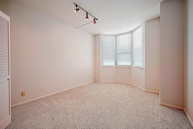 651 Bering Dr Unit 1101, Houston, TX 77057 - unfurnished room with a textured ceiling, carpet, rail lighting, and baseboards