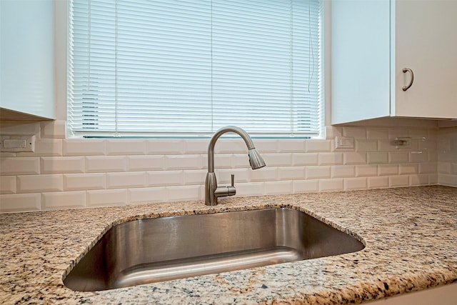 651 Bering Dr Unit 1101, Houston, TX 77057 - kitchen view of a sink, white cabinetry, backsplash, and light stone counters
