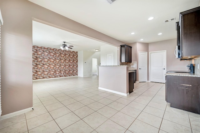 21114 Echo Manor Dr, Hockley, TX 77447 - kitchen with brick wall, dark brown cabinetry, light tile patterned flooring, stove, and open floor plan