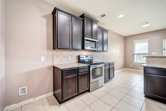 21114 Echo Manor Dr, Hockley, TX 77447 - kitchen featuring appliances with stainless steel finishes, tasteful backsplash, light stone countertops, light tile patterned floors, and recessed lighting