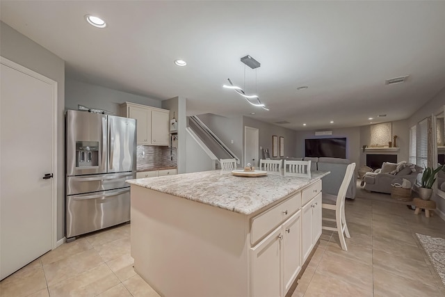 3126 Silverstag Trail Ln, Houston, TX 77073 - kitchen featuring stainless steel refrigerator with ice dispenser, light tile patterned floors, a kitchen island, light stone counters, and hanging light fixtures