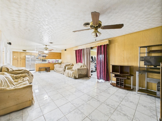 8206 Dillon St, Houston, TX 77061 - living area featuring ceiling fan, wooden walls, a textured ceiling, and light tile patterned flooring
