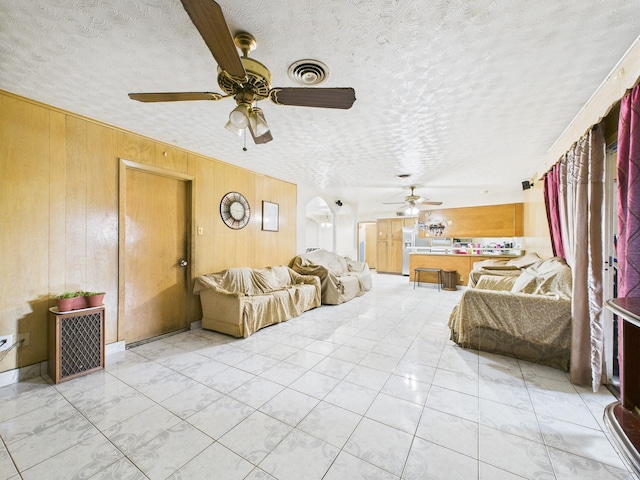 8206 Dillon St, Houston, TX 77061 - living room featuring a ceiling fan, wooden walls, a textured ceiling, and arched walkways