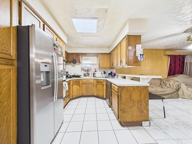8206 Dillon St, Houston, TX 77061 - kitchen featuring stainless steel appliances, a peninsula, open floor plan, brown cabinets, and a breakfast bar area