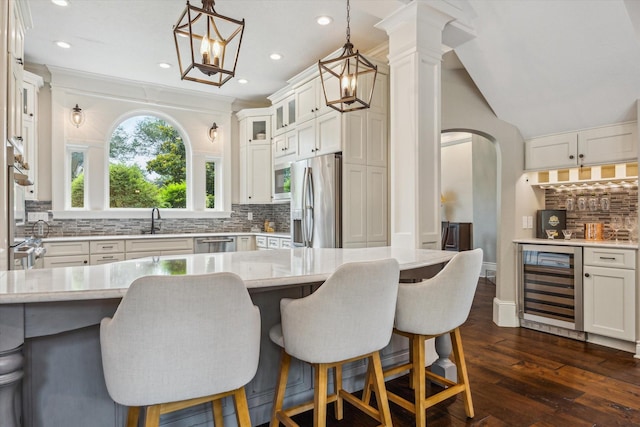 1902 Carriage Creek Ln, Friendswood, TX 77546 - kitchen with beverage cooler, stainless steel appliances, tasteful backsplash, a sink, and a kitchen bar