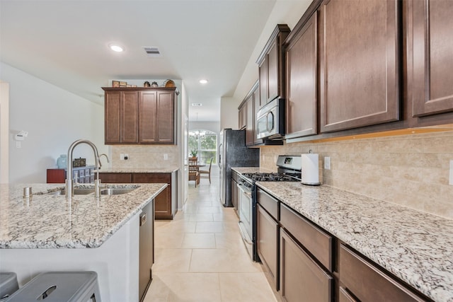 23715 Rivage Ridge Dr, Katy, TX 77493 - kitchen with appliances with stainless steel finishes, a sink, light stone countertops, light tile patterned floors, and decorative backsplash