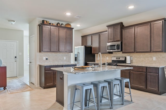 23715 Rivage Ridge Dr, Katy, TX 77493 - kitchen with stainless steel appliances, dark brown cabinets, a sink, a kitchen bar, and backsplash