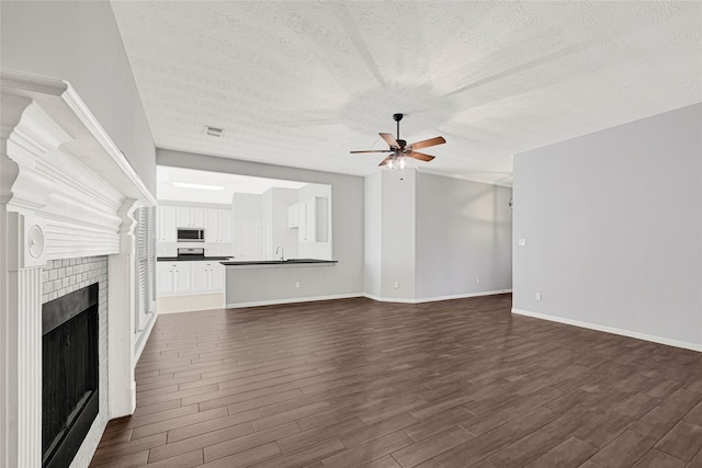 7818 Silver Lure Dr, Humble, TX 77346 - unfurnished living room with ceiling fan, dark wood finished floors, a textured ceiling, a fireplace, and baseboards
