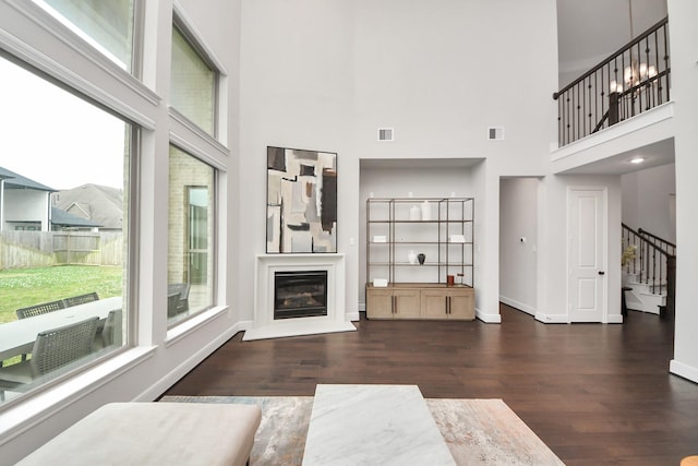 12813 N Palomino Lake Cir, Cypress, TX 77429 - unfurnished living room with wood finished floors, stairway, a glass covered fireplace, a high ceiling, and baseboards