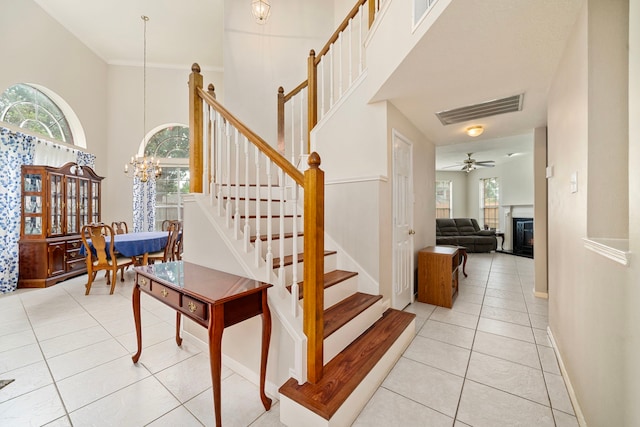9715 Therrell Dr, Houston, TX 77064 - staircase with tile patterned floors, a glass covered fireplace, a towering ceiling, baseboards, and ceiling fan