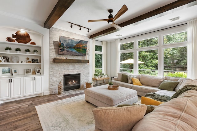 38 Agate Stream Pl, The Woodlands, TX 77381 - living area featuring beamed ceiling, a ceiling fan, wood finished floors, a stone fireplace, and built in shelves