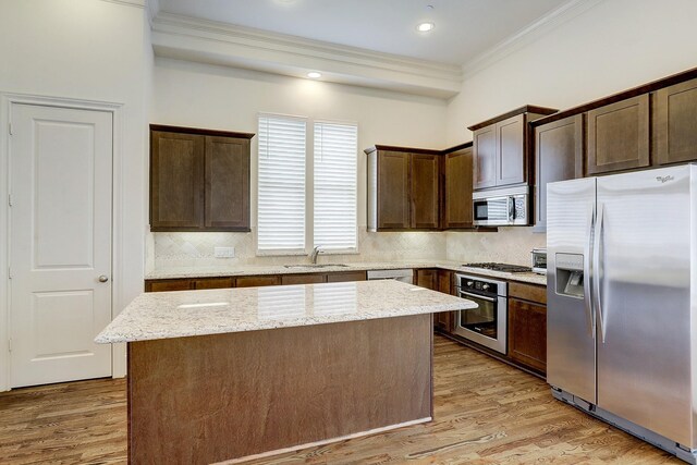 9622 Fannin Sta W, Houston, TX 77045 - kitchen with appliances with stainless steel finishes, crown molding, a center island, dark brown cabinetry, and backsplash