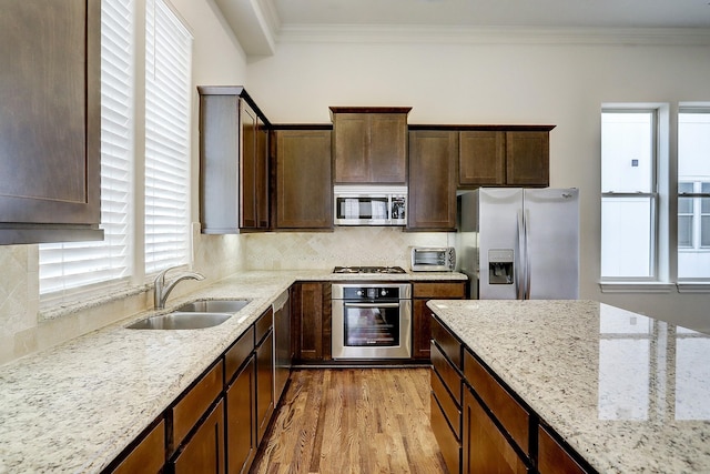 9622 Fannin Sta W, Houston, TX 77045 - kitchen with stainless steel appliances, a sink, light wood-style flooring, ornamental molding, and light stone countertops