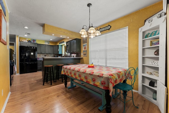 3027 Pine Acres Dr, Conroe, TX 77384 - dining area featuring a chandelier, light wood finished floors, a textured ceiling, and baseboards