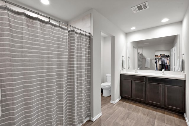 13916 Great Pines Ct, Conroe, TX 77302 - bathroom featuring toilet, wood finished floors, double vanity, recessed lighting, and a spacious closet