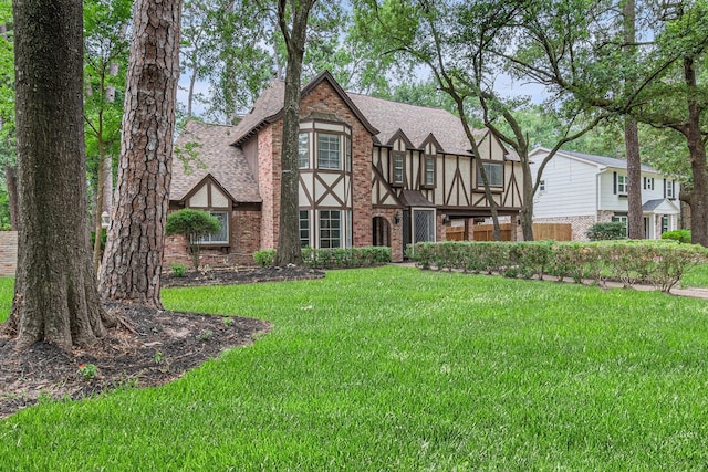 6307 Bayonne Dr, Spring, TX 77389 - tudor home featuring roof with shingles, brick siding, and a front yard