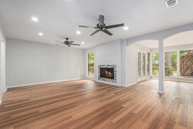 6307 Bayonne Dr, Spring, TX 77389 - unfurnished living room with arched walkways, recessed lighting, wood finished floors, baseboards, and a stone fireplace