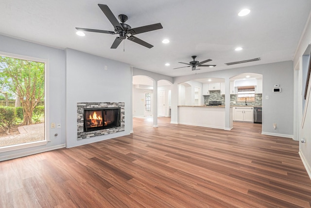 6307 Bayonne Dr, Spring, TX 77389 - unfurnished living room featuring arched walkways, ceiling fan, a stone fireplace, baseboards, and wood finished floors