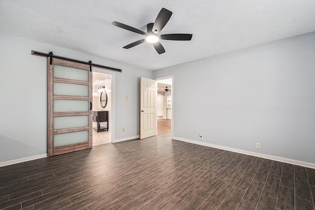6307 Bayonne Dr, Spring, TX 77389 - unfurnished bedroom with a barn door, dark wood-style flooring, baseboards, and a ceiling fan