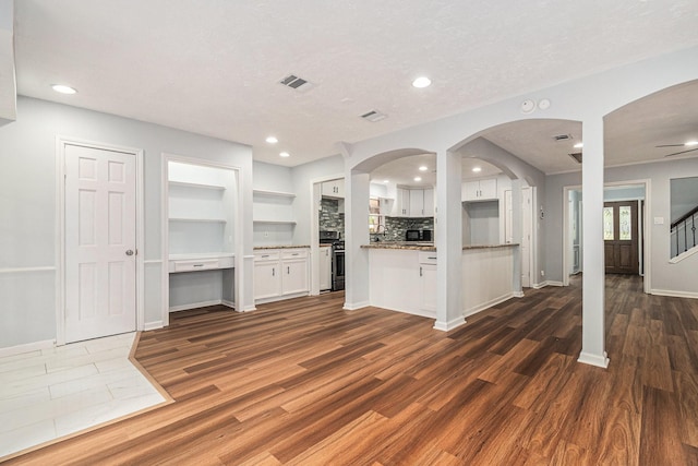 6307 Bayonne Dr, Spring, TX 77389 - unfurnished living room featuring dark wood finished floors, baseboards, recessed lighting, arched walkways, and stairs