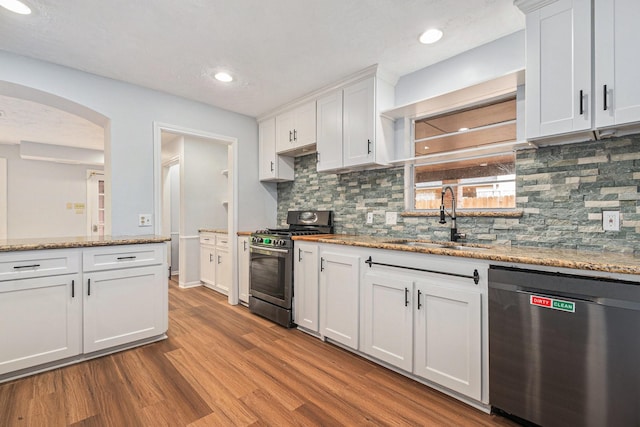 6307 Bayonne Dr, Spring, TX 77389 - kitchen with stainless steel appliances, a sink, wood finished floors, white cabinets, and tasteful backsplash